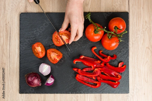 Obraz Top down view on cutting board with hands slicing vegetables