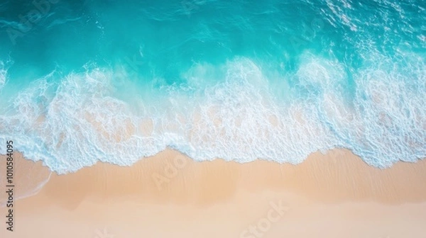 Fototapeta An aerial view of a sandy beach and turquoise ocean waves crashing on the shore.