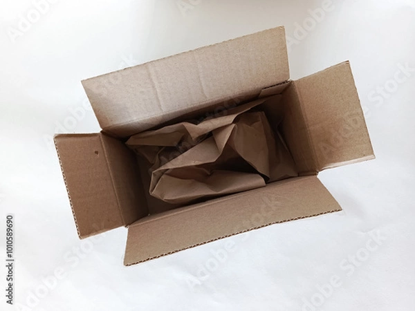 Fototapeta Open cardboard box on white background. Box with paper filler for packing fragile items. Product packaging. Background.