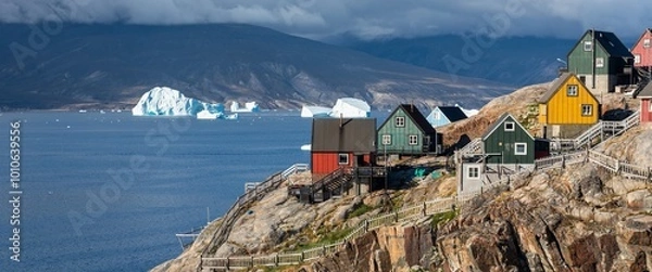 Fototapeta Baffin Bay, the colorful typical houses in the small village of Uummannaq, the Greenland. Icefjord in Greenland and the silhouette of the high mountain ridge in the background under the blue melting g