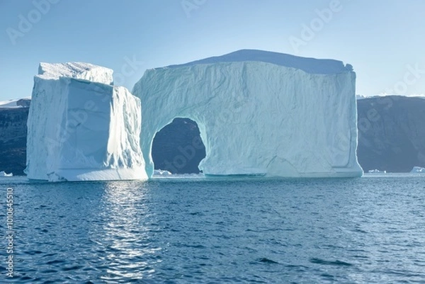Fototapeta A massive iceberg with arch. Melting of a glacier by the coast of Greenland. Amazing iceberg on the sea, we can still see this before complete climate change. Icefjord Global warming.