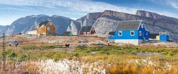 Fototapeta Panoramic view of colorful village in East Greenland. Houses in the small village during summer sunny day. Icebergs and mountains in the background. Typical buildings for Greenland. Romantic landscape