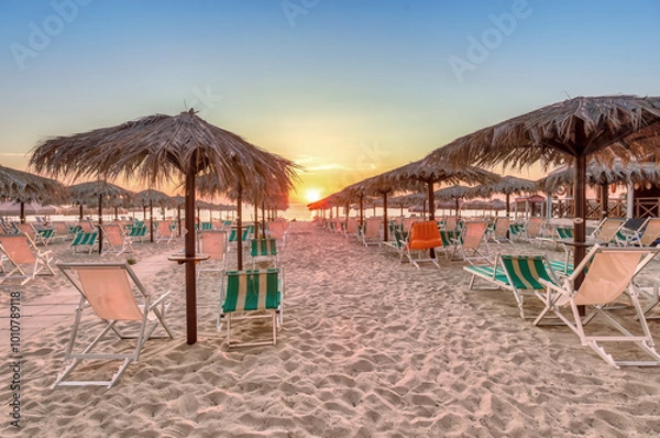 Fototapeta Captivating sunset at Silvi Marina beach on the Adriatic coast of Italy with colorful beach chairs and scenic views, coast of the Abruzzo region.