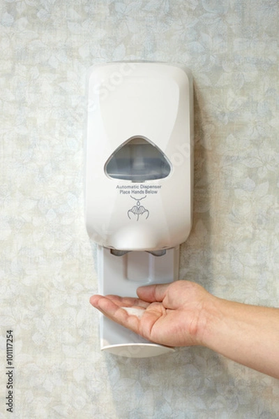 Fototapeta Person Using Wall Mounted Hand Sanitizer