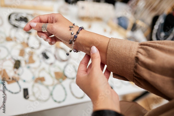 Obraz Hands of a woman with a beautiful pink manicure, trying on jewelry in the form of rings and bracelets.