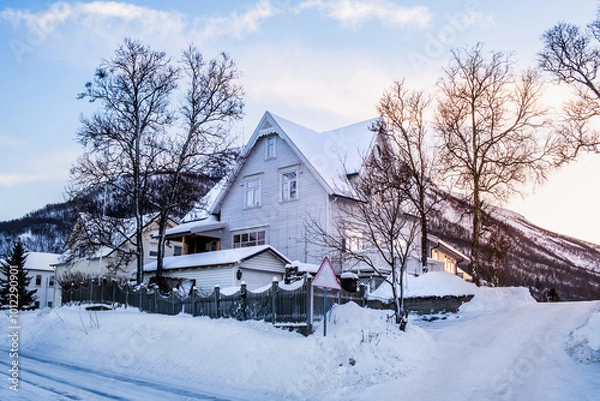 Fototapeta White wooden house in winter landscape of nordic town Tromso, Norway. Scandinavian generic architecture on Tromsoya island in Arctic circle. Winter wonderland with a lot of snow