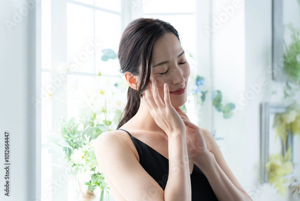 Fototapeta 窓に立ち肌に触れるワンピースを着た女性