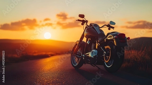 Fototapeta A motorcycle parked on the right side of the road during sunset, with a blurred background creating a peaceful atmosphere