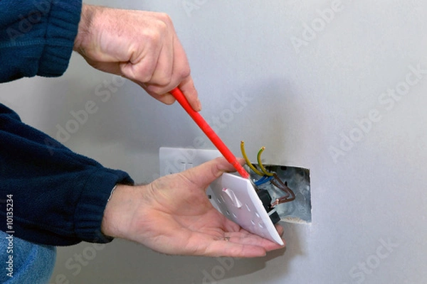 Obraz Ręce elektryka instalującego gniazdko elektryczne