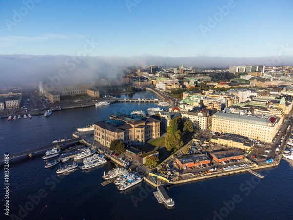 Fototapeta Fog rolling in over the royal palace and the old city of Stockholm, aerial view. Bright blue sky above