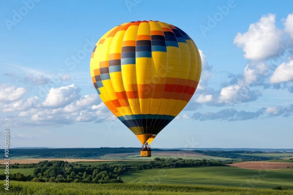 Fototapeta Hot air balloon floating in blue sky surrounded by soft clouds
