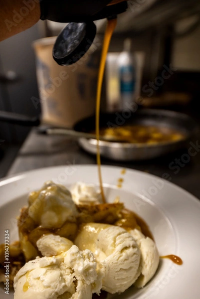 Fototapeta Cheese cake, bananas, caramel dessert. Making dessert behind the scenes. Vanilla Ice cream, whip cream topped on cheese cake, banana sauce topping with caramel on top. 