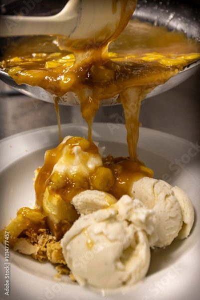 Fototapeta Cheese cake, bananas, caramel dessert. Making dessert behind the scenes. Vanilla Ice cream, whip cream topped on cheese cake, banana sauce topping with caramel on top. 
