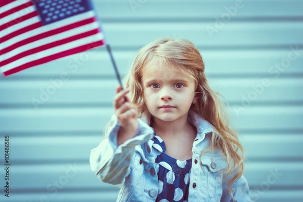 Obraz Adorable little girl with long curly blond hair holding american flag and waving it. Independence Day, Flag Day concept. Vintage and toning