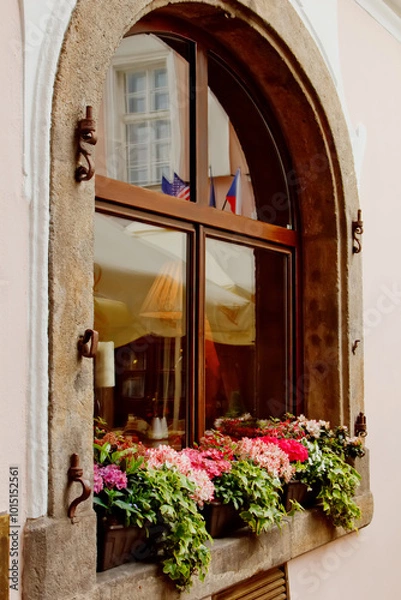 Fototapeta Prague. 05.11.2019: Famous facades of Prague. Beautiful balcony with flowers against a brown-orange wall. Beautiful flowers set up on windowsill exterior.