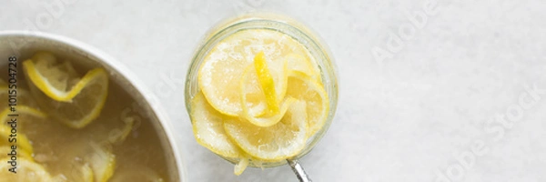 Obraz lemon cheong in a glass jar on a white background, korean lemon cheong in a transparent jar, lemon slices in sugar syrup