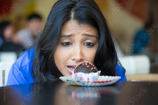 Obraz Closeup portrait of desperate woman in blue shirt craving fudge with pink sprinkles dessert, eager to eat, isolated indoors background