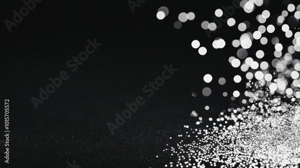 Fototapeta Shimmering silver glitter scattered on a black background, creating a festive and elegant backdrop.