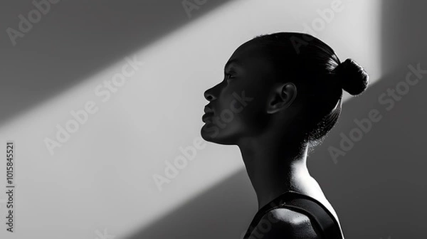Fototapeta A moody black and white image of a model standing against a plain background, with dramatic high-contrast lighting casting long shadows behind. 8k UHD, suitable for high-quality printing or 