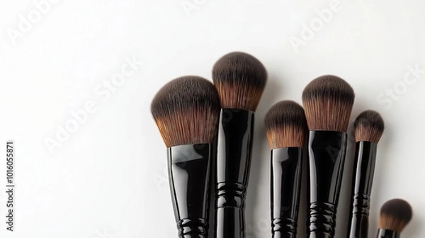 Fototapeta Elegant makeup brushes featuring brown bristles and black handles, placed against a minimalist white backdrop.