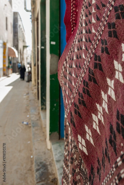 Fototapeta Tripoli, Libya, 4 November 2009.  A quiet street in the old city of Tripoli, Libya, with a rug hanging on the side of the wall and pedestrians in the background.
