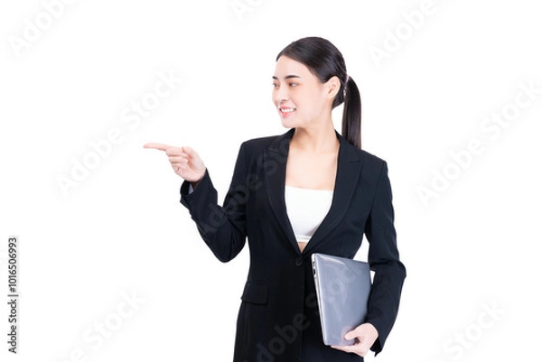 Fototapeta Professional young businesswoman in a black suit smiling and pointing while holding a tablet, representing modern technology, leadership, and communication in corporate world.