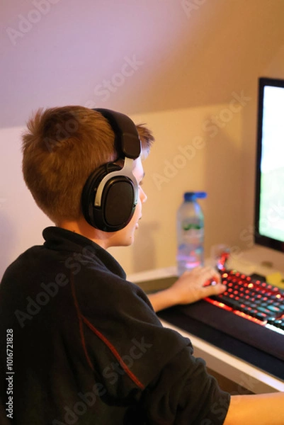Obraz Close up of a teenage boy playing a game on the computer with headphones on