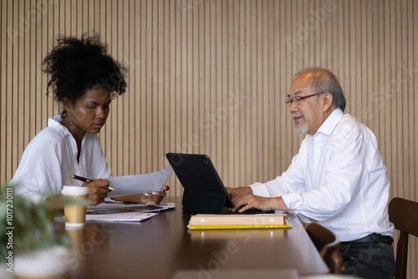 Obraz Business team with senior management and officer  collaborating in an office setting with professionals working together on laptops and engaging in conversation