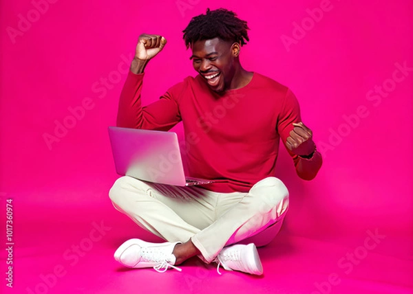 Obraz Young black man sitting on the floor with a laptop dancing and having fun