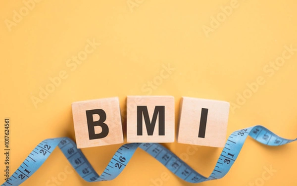 Obraz Wooden block displaying 'BMI' next to a measuring tape on yellow background. The concept of Body Mass Index, highlighting the importance of health metrics in tracking fitness and well-being