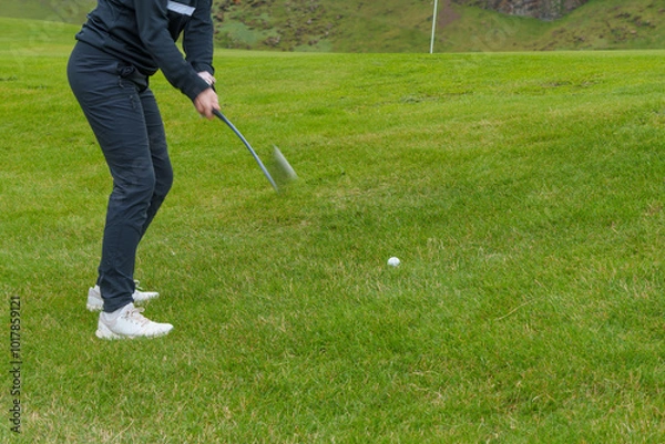 Fototapeta Golfer swinging a club on a grassy course