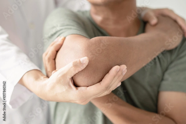 Obraz Female physiotherapists provide assistance to male patients with elbow injuries examine patients in rehabilitation centers. Physiotherapy concepts