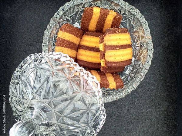 Fototapeta A crystal jar filled with delicious, striped cookies. The cookies, featuring alternating layers of chocolate and vanilla, look incredibly tempting. The jar's lid is partially open.