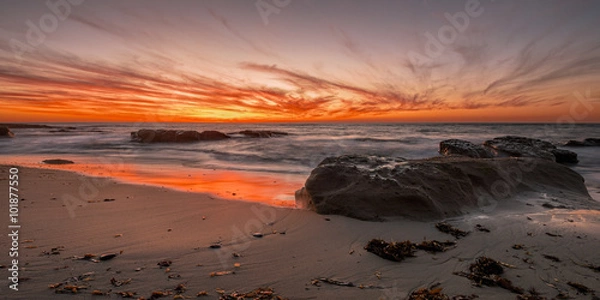Fototapeta Color My World-  Clouds turn brilliant orange, red and yellow as the sun sets over the Pacific Ocean splashing colors over clouds, water and sand. This is Bermuda Beach in San Diego, California.