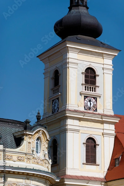 Fototapeta A baroque-style church tower in Sibiu, Romania, featuring an onion-shaped dome, a clock face, and arched windows.                  