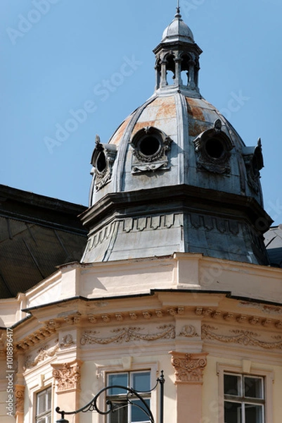 Fototapeta A close-up of a historic building showcases its distinctive dome, adorned with intricate details.  However, a section of the roof is in urgent need of repair, revealing signs of neglect.