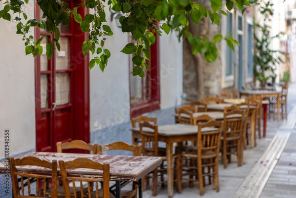 Obraz Rustic wooden tables and chairs create an inviting atmosphere in Nafplio, Greece, inviting visitors to relax and savor local delicacies in this picturesque setting.