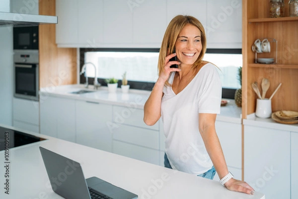 Obraz Woman Smiling While Talking on Phone in Kitchen