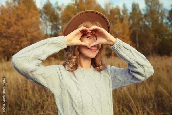 Fototapeta Beauty portrait of stylish happy young woman showing heart gesture, girl smiling in autumn park