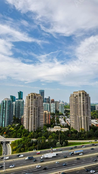 Fototapeta Aerial views of high-rise residential buildings near the 401 expressway and Yonge Street in Toronto. The bustling highway, surrounded by lush greenery and modern architecture, creates a dynamic