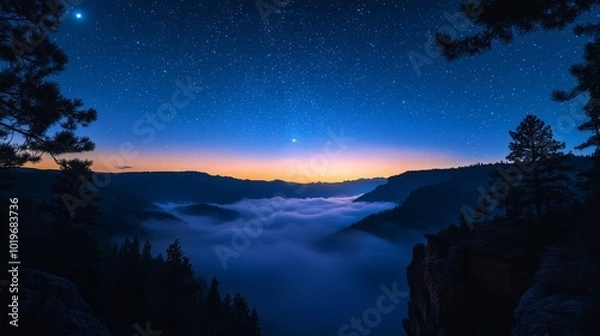 Fototapeta A ring of silhouetted pine trees at the edge of a mountain cliff, framing a valley filled with glowing fog, under a starlit sky