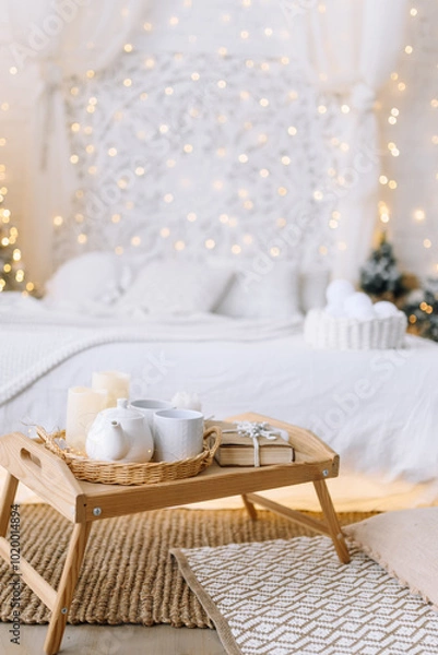 Fototapeta A tray with hot tea, gifts and candles in a festively decorated room. Soft light and Christmas decor create a magical atmosphere of winter peace and comfort. Vertical photo with space for text