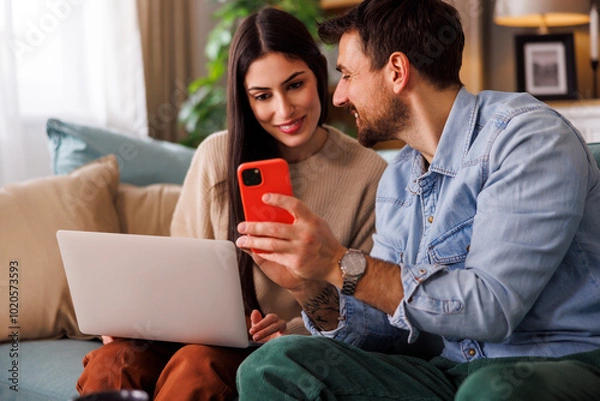 Fototapeta Couple of vloggers editing and posting theit new video online