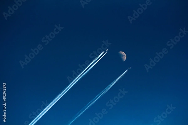 Fototapeta two aircraft flying in the sky next to the moon