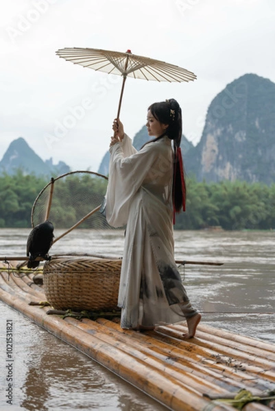 Obraz Hanfu girl with deng looking at mountainous landscape from raft on Li river, China. Vertical
