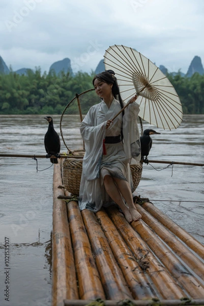 Obraz Hanfu girl with umbrella on bamboo raft in Xingping posing with cormorants