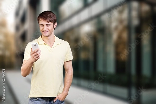 Obraz Happy young man hold phone and posing on street background