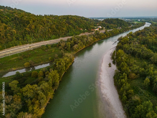 Fototapeta Aerial view of Sava river shoreline at sunset, with both embankments overgrown in dense forest