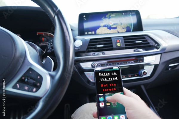 Fototapeta focus on the road not the screen. someone with the phone in his hand, driving