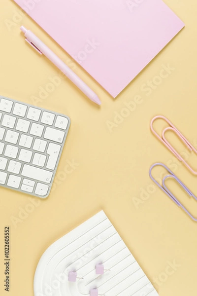 Obraz Top view of white keyboard, pink notebook, pink pen on yellow background. Paper clips, pins, modern office, school. White arch tray, flat lay, copy space.